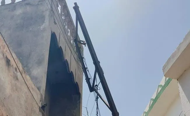 मकान की रेलिंग पर टिका विद्युत पोल, हादसे की आशंका