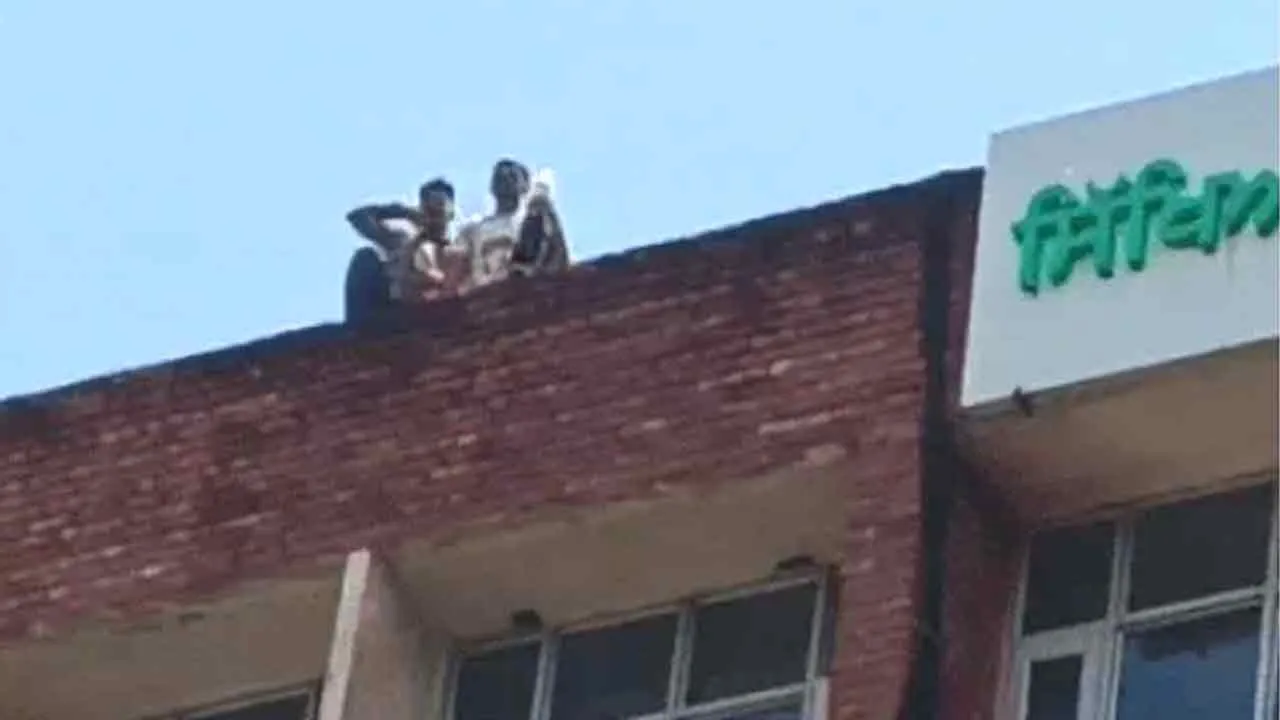 शिक्षा बोर्ड की ऊपरी मंजिल पर चढ़े दो युवक