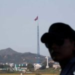 A South Korean soldier stands guard as a North Korean flag flutters on top of a tower at the propaganda village of Gijungdong in North Korea, in this picture taken near the truce village of Panmunjom